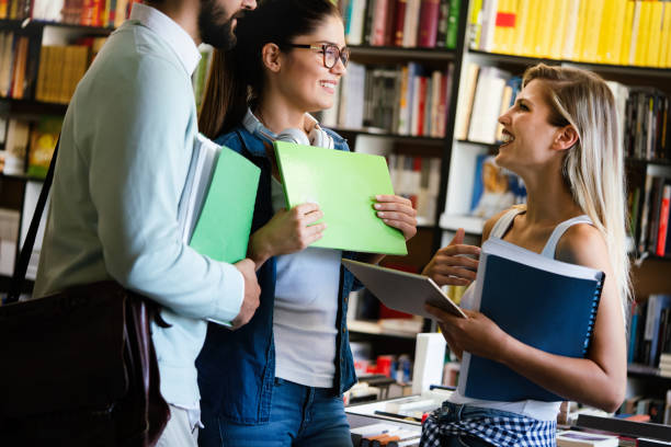 istock Group of happy college students studying at campus library together 1280120624