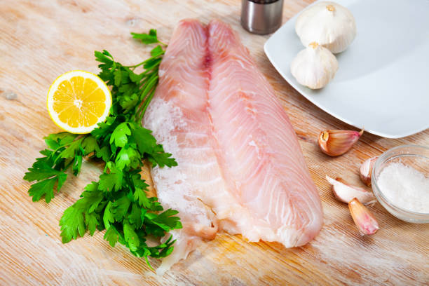 istock Perch fillet on cutting board with lemon and parsley. 1280122667