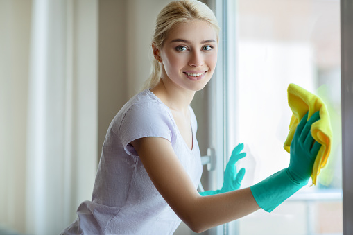 Young Woman cleaning window glass