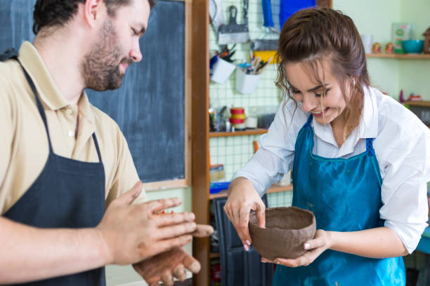 istock Claymaking Process Concept. Two Cheerful Professional Ceramists During a Process of Clay Preparation on Tables in Workshop. Horizontal Image Orientation 1280127902