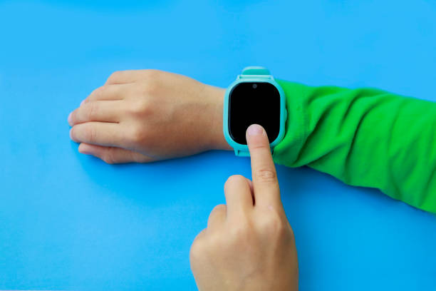 istock boy looks at information on digital clock pressing screen with his index finger. Modern childrens technologies. GPS tracker for kids, child tracking and parental control concept. 1280128205