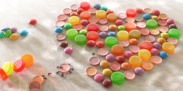 A conceptual image of ants working together in harmony arranging sweets in the shape of a heart. A small team of ants surround a sweet and are manoeuvring it towards the heart. Another pair are moving out the next sweet, and another ant directs them towards the gap.