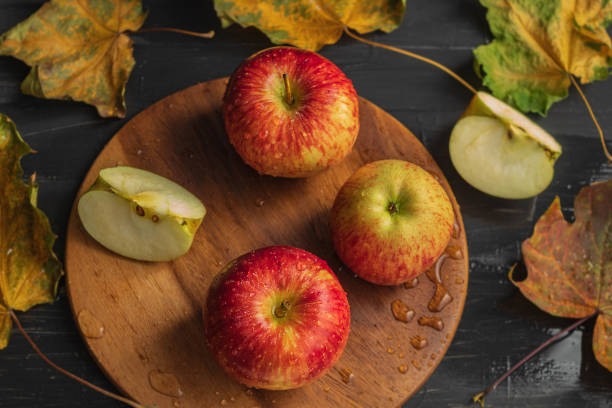 istock Three whole red apples and one apple, cut in half on a black background 1280129455