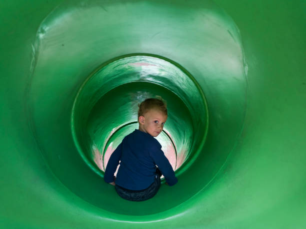 niño niño sentado en slider of kid playground - beck fotografías e imágenes de stock