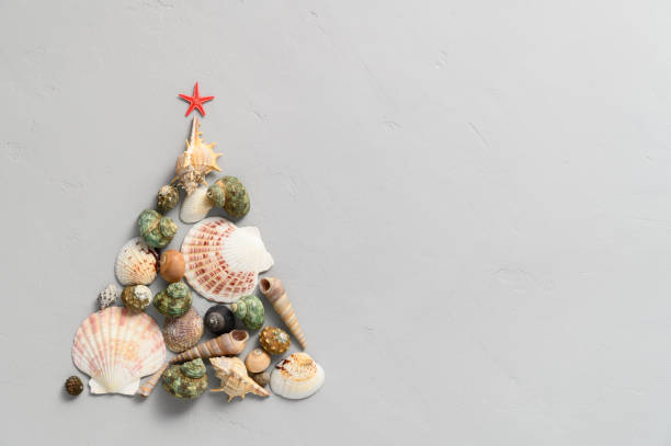 istock Alternative Christmas tree made from seashells and with a red starfish on a light gray background. 1280130542