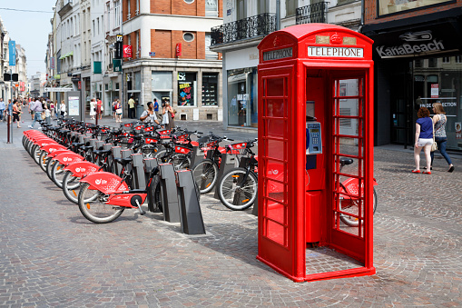 Lille, France - July 18, 2013. Red British telephone box and free bike rental station in a street in Lille, France
