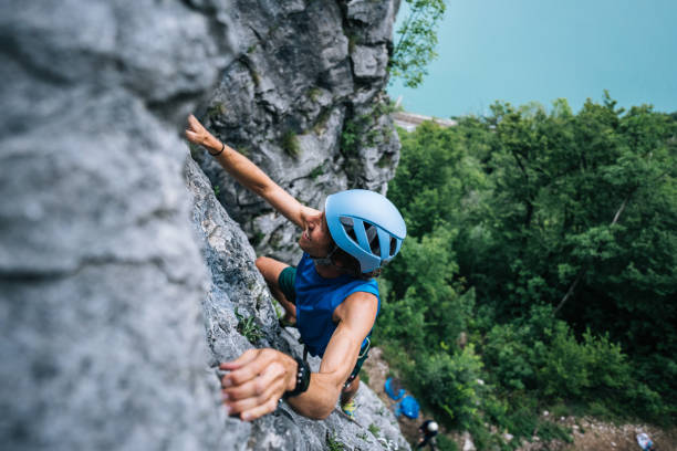 view of man climbing up mountain ridge above lake - leadership risk cliff mountain climbing imagens e fotografias de stock