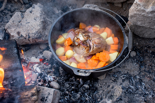 Dutch oven campfire cooking process - lamb and vegetables in a cast iron camp oven, Camping life.