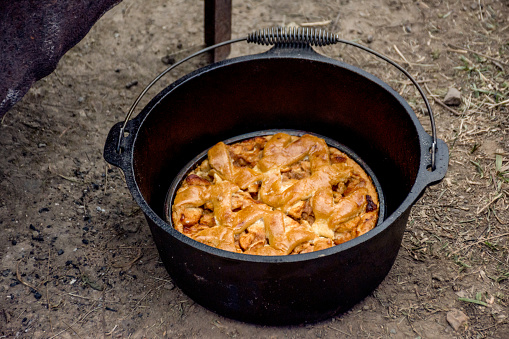Dutch oven campfire cooking - baking an apple pie in cast iron camp oven. Camping life