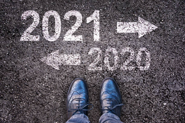 istock 2021 and 2020 with direction arrows written on an asphalt road background with legs 1280135321
