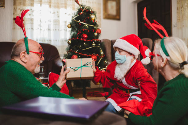 istock Cute boy with his grandparents wearing facemask while celebrating Christmas at home during the COVID-19 pandemic 1280135524