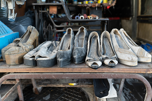Worn high-heeled women's shoes on display in a shoe repair shop