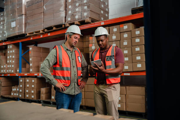 istock Male colleagues wearing overalls researching on digital tablet packaging processes standing in warehouse 1280140263
