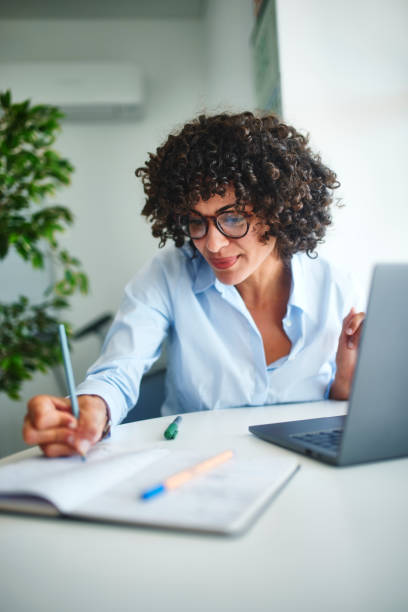 istock Business woman writing notes and working on laptop in office 1280147348
