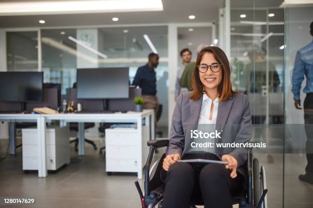 Disabled Business Woman In Wheelchair Holding Table Smiling In Office Stock Photo - Download Image Now