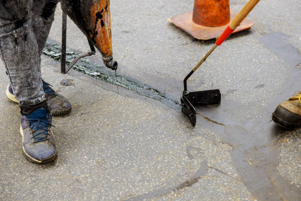 istock Road surface restoration work in the worker performs on road patcher work on the repair of cracks by filling and sealing with coated by bitumen emulsion 1280149865