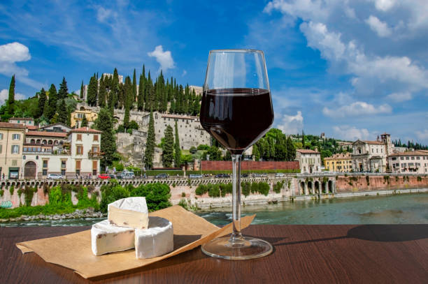bicchiere di vino rosso e formaggio brie con vista sulle rovine romane e sul fiume a verona, italia - verona foto e immagini stock