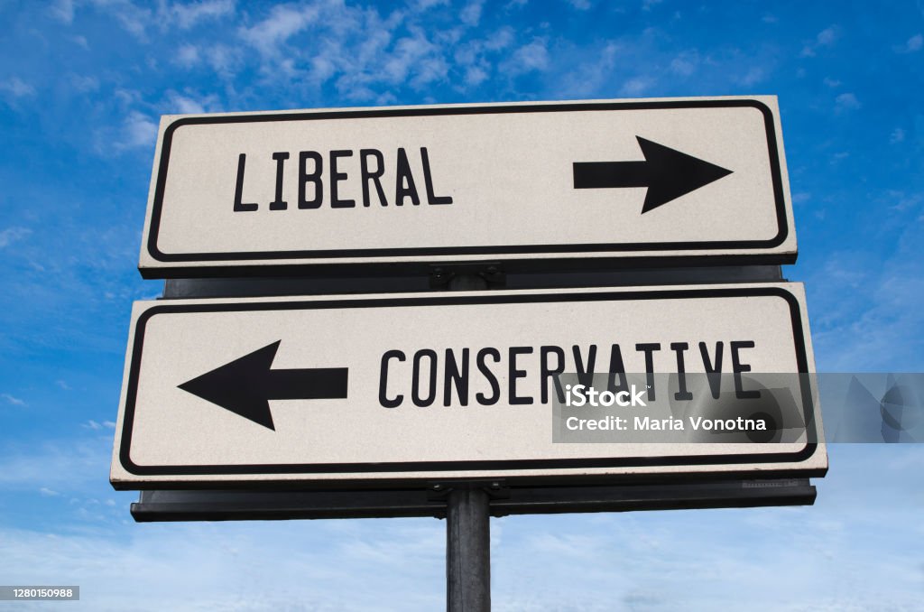 Liberal vs conservative. White two street signs with arrow on metal pole with word. Directional road. Crossroads Road Sign, Two Arrow. Blue sky background. Two way road sign with text. Democratic Party - USA Stock Photo