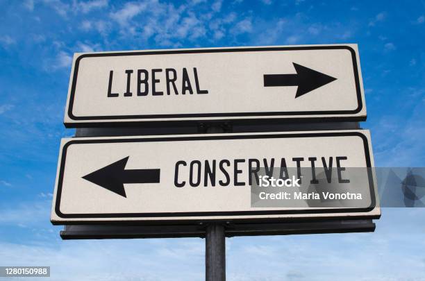 Liberal Vs Conservative White Two Street Signs With Arrow On Metal Pole With Word Directional Road Crossroads Road Sign Two Arrow Blue Sky Background Two Way Road Sign With Text Stock Photo - Download Image Now