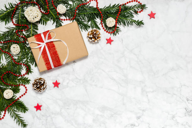 istock Christmas handmade gift box, conifer tree branches, pine cones, beads garland, stars on marble background. Winter holiday theme. Merry Christmas and Happy New Year greeting card with copyspace 1280152289