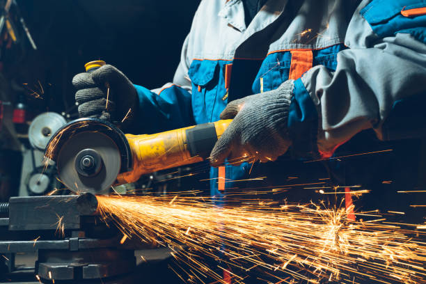 istock Locksmith in special clothes and goggles works in production. Metal processing with angle grinder. Sparks in metalworking 1280155126