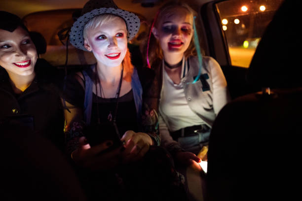 istock Smiling young women, talking with a driver and  while driving to Halloween party 1280159084