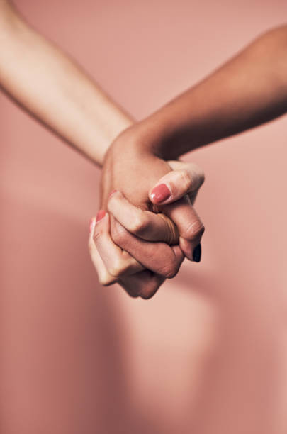 We're capable of so much when we stand together Shot of two unrecognizable women holding hands against a pink background racial equality photos stock pictures, royalty-free photos & images