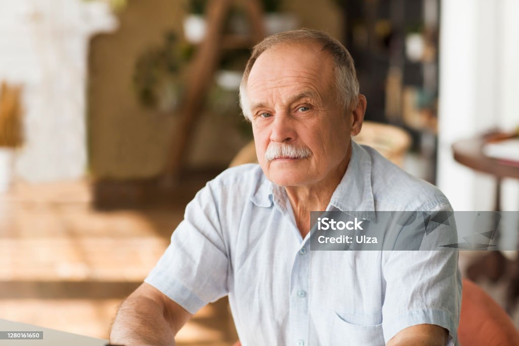 portrait senior man thinking and looking at camera at home Men Stock Photo