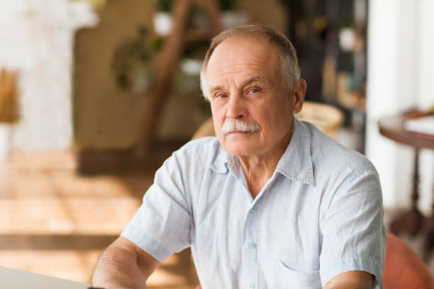 portrait senior man thinking and looking at camera at home portrait senior man thinking and looking at camera at home 60 69 years stock pictures, royalty-free photos & images