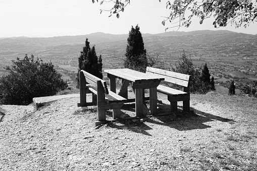 An empty wooden picnic table with wooden benches in a park with a panoramic view (Gubbio, Umbria, Italy, Europe)