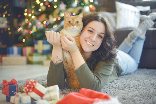 young woman in christmas interior with ginger cat