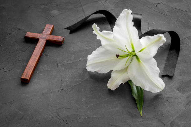 istock White lily with cross and black ribbon. Funeral concept 1280164382