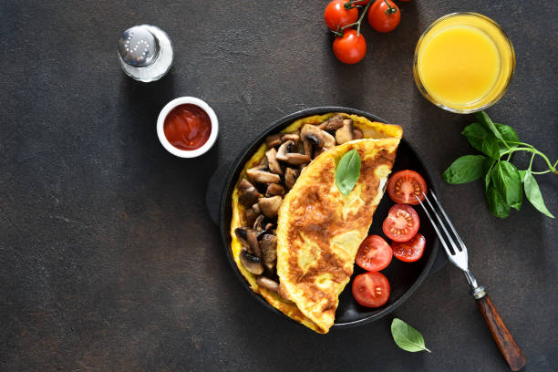 istock Omelet with mushrooms and tomatoes for breakfast with orange sticks on a concrete background. 1280170990