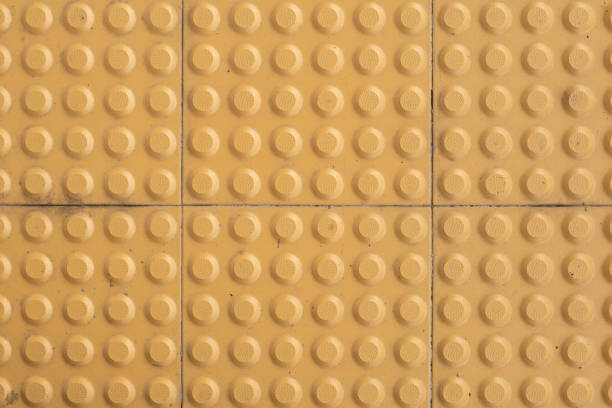 yellow anti-slip tile, fragmented on the pavement, symbolizing disruption and the fragility of safety in urban spaces