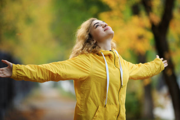 istock Woman in yellow jacket with raised hands enjoy a fall day 1280173438