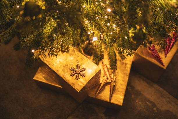 istock golden presents under illuminated christmas tree at home 1280173443