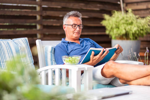 istock Senior man sitting on home terrace and reading a book 1280173548