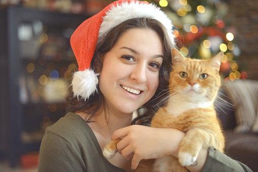 young woman in christmas interior with ginger cat