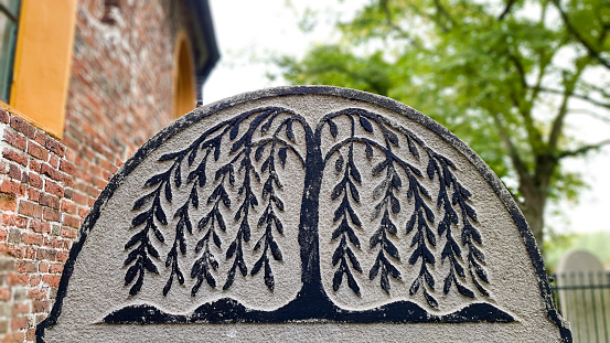 Groningen, the Netherlands - September 26, 2020: Close-up of gravestone on which a symbolic black colored tree of life or weeping willow has been carved.