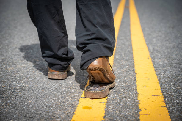 Cropped shot of man walking on the road while wearing torn broken shoes.