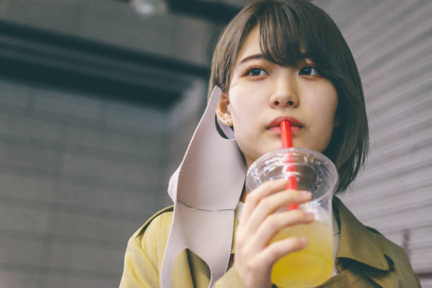 New normal concept,  Asian woman take off the mask at outside and drinking take out drink.