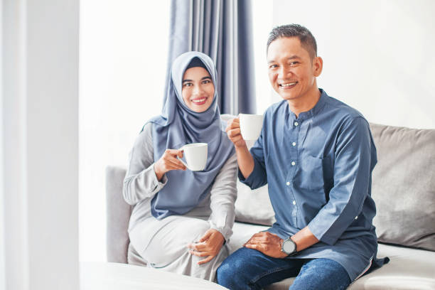 Meeting of two muslim people over coffee Beautiful indonesian muslim couple drinking coffee at home malay couple stock pictures, royalty-free photos & images