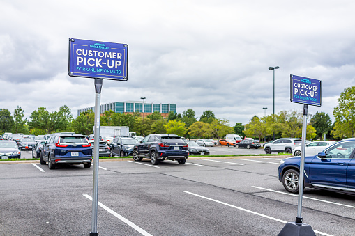 Sterling, USA - September 12, 2020: World Market parking lot store sign by entrance of store in Loudoun county, Virginia for customer pick-up with cars