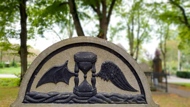 Groningen, the Netherlands - September 26, 2020:  Close up of a tombstone in an old cemetery on which an hourglass with wings has been carved, depth of field, Dutch culture.