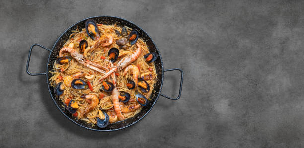 paella de pasta de marisco, cocina española sobre fondo rústico - copiar espacio - fideua fotografías e imágenes de stock