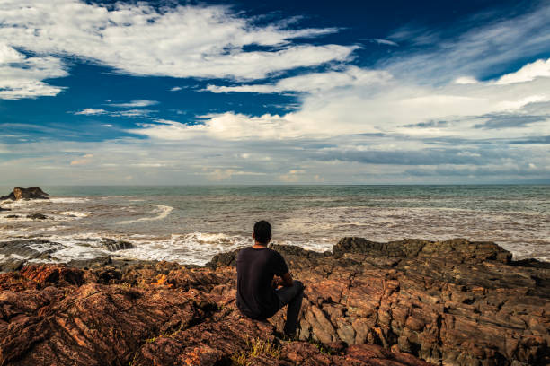 Pondicherry, November 2022 : a man talks on the 'phone while a dog, probably a stray, chills on the beach.