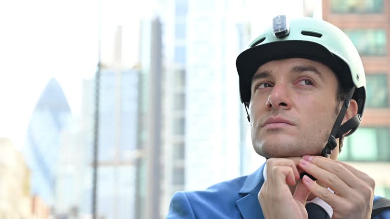 Mid adult businessman putting on helmet and cycling away