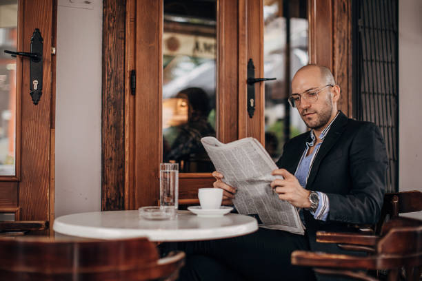 istock One handsome businessman reading newspaper in sidewalk cafe 1280184053