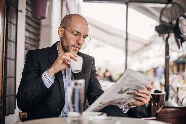 istock Young businessman drinking coffee and reading newspaper in sidewalk cafe 1280184084