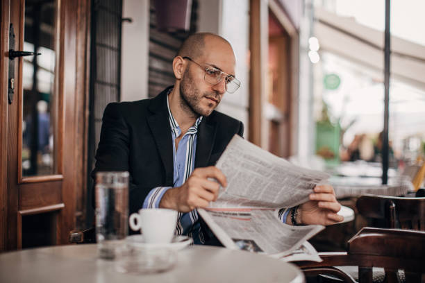 istock Handsome businessman reading newspaper in sidewalk cafe 1280184114